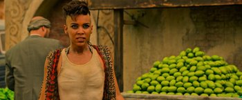 Movie still from “X-Men: Apocalypse” (2016), directed by Bryan Singer – A woman standing in front of a pile of green fruit; Close Up shot, Over the shoulder angle