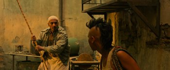 Movie still from “X-Men: Apocalypse” (2016), directed by Bryan Singer – A man with a shaved head talking to another man in an alley; Medium shot, Over the shoulder angle