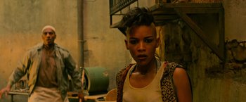 Movie still from “X-Men: Apocalypse” (2016), directed by Bryan Singer – A woman with a shaved head is looking at the camera; Close Up shot, Over the shoulder angle
