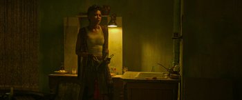 Movie still from “X-Men: Apocalypse” (2016), directed by Bryan Singer – A woman standing in a dimly - lit kitchen holding a phone; Medium shot, Low angle