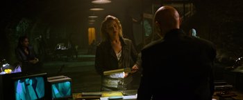 Movie still from “X-Men: Apocalypse” (2016), directed by Bryan Singer – A woman standing in front of a man in a dark room; Medium shot, Over the shoulder angle