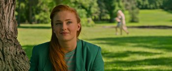 Movie still from “X-Men: Apocalypse” (2016), directed by Bryan Singer – A woman with red hair sitting in the grass; Close Up shot, Over the shoulder angle