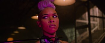 Movie still from “X-Men: Apocalypse” (2016), directed by Bryan Singer – A woman with a purple mohawk and a stick in her hair; Close Up shot, Low angle