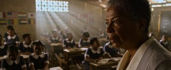 Movie still from “X-Men: Apocalypse” (2016), directed by Bryan Singer – An older woman is looking at the camera in a class room; Close Up shot, Over the shoulder angle