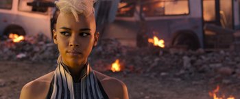Movie still from “X-Men: Apocalypse” (2016), directed by Bryan Singer – A woman with a white mohawk is standing in front of a fire pit; Close Up shot, Over the shoulder angle