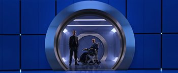 Movie still from “X-Men: Apocalypse” (2016), directed by Bryan Singer – Two men standing in a room with a wheel chair; Wide shot, Low angle