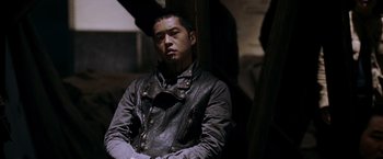 Movie still from “X-Men: The Last Stand” (2006), directed by Brett Ratner – A man in a leather jacket sitting in a dark room; Medium shot, Low angle