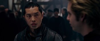 Movie still from “X-Men: The Last Stand” (2006), directed by Brett Ratner – A man in a black leather jacket with tattoos on his face; Close Up shot, Over the shoulder angle