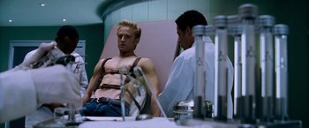 Movie still from “X-Men: The Last Stand” (2006), directed by Brett Ratner – A man is sitting in a chair with a doctor; Medium shot, Low angle