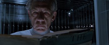 Movie still from “X2” (2003), directed by Bryan Singer – An older man looking at the camera in a dimly - lit room; Close Up shot, Low angle