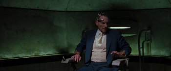 Movie still from “X2” (2003), directed by Bryan Singer – An older man in a blue suit and a white shirt is sitting in front of a green wall; Medium shot, Over the shoulder angle