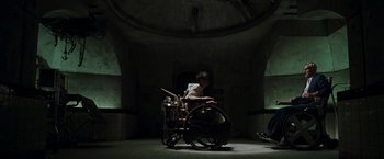 Movie still from “X2” (2003), directed by Bryan Singer – A man sitting on a wheel chair in a dark room; Wide shot, Overhead angle