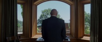 Movie still from “X2” (2003), directed by Bryan Singer – A man in a suit looking out a window; Medium shot, Low angle