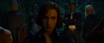 A woman in a black jacket standing in front of two men