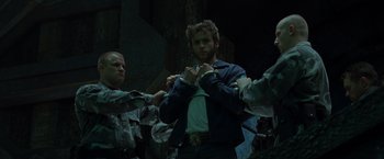 Movie still from “X2” (2003), directed by Bryan Singer – A group of men holding hands around a man in a blue jacket; Medium shot, Low angle