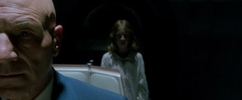 Movie still from “X2” (2003), directed by Bryan Singer – A woman standing in a dark room next to a chair; Close Up shot, Over the shoulder angle