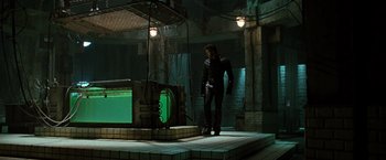 Movie still from “X2” (2003), directed by Bryan Singer – A man standing in front of a television in a dark room; Wide shot, High angle
