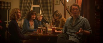 Movie still from “Yesterday” (2019), directed by Danny Boyle – A group of people sitting at a table with drinks; Medium shot, Over the shoulder angle