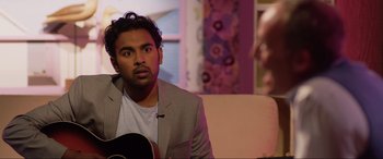 Movie still from “Yesterday” (2019), directed by Danny Boyle – A man sitting in front of a guitar in a room; Close Up shot, Over the shoulder angle