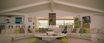Movie still from “Yesterday” (2019), directed by Danny Boyle – A woman sitting in front of a table in a living room; Wide shot, High angle