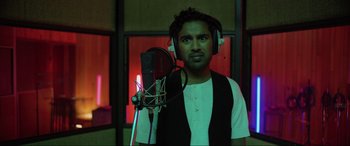 Movie still from “Yesterday” (2019), directed by Danny Boyle – A man wearing headphones and standing in front of a microphone in a recording studio; Close Up shot, Low angle