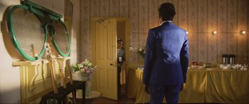 Movie still from “Yesterday” (2019), directed by Danny Boyle – A man in a blue suit is looking in the mirror; Wide shot, Over the shoulder angle