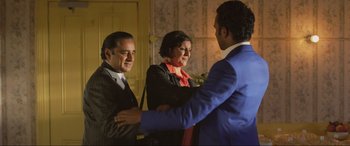 Movie still from “Yesterday” (2019), directed by Danny Boyle – Two men and a woman are shaking hands in a room; Medium shot, Over the shoulder angle