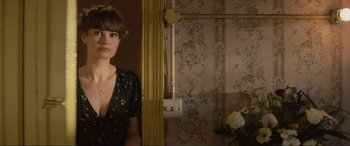 Movie still from “Yesterday” (2019), directed by Danny Boyle – A woman standing next to a door in a room with floral wallpaper; Medium shot, Over the shoulder angle