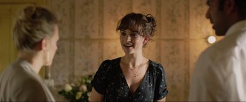 Movie still from “Yesterday” (2019), directed by Danny Boyle – A woman in a black dress smiling for the camera; Close Up shot, Over the shoulder angle