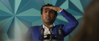 Movie still from “Yesterday” (2019), directed by Danny Boyle – A man standing in front of microphones with one hand up to his forehead; Medium shot, Low angle