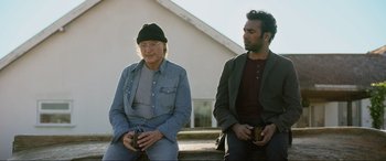Movie still from “Yesterday” (2019), directed by Danny Boyle – Two men sitting on steps next to each other; Medium shot, Over the shoulder angle