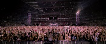 Movie still from “Yesterday” (2019), directed by Danny Boyle – A crowd of people at an event holding up cell phones in the air; Extreme Wide shot, High angle