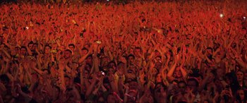 Movie still from “Yesterday” (2019), directed by Danny Boyle – A crowd of people at an event raising their hands; Extreme Wide shot, High angle
