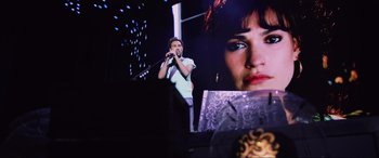 Movie still from “Yesterday” (2019), directed by Danny Boyle – A man singing into a microphone in front of an image of a woman's face; Medium shot, Over the shoulder angle