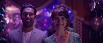 Movie still from “Yesterday” (2019), directed by Danny Boyle – A woman smiles at the camera while standing next to a man; Close Up shot, Over the shoulder angle