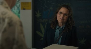 Movie still from “You Hurt My Feelings” (2023), directed by Nicole Holofcener – A woman in glasses and a jacket sitting at a table; Medium shot, Over the shoulder angle