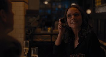 Movie still from “You Hurt My Feelings” (2023), directed by Nicole Holofcener – A woman sitting at a table with a cell phone in her hand; Medium shot, Over the shoulder angle