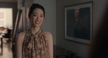Movie still from “You Hurt My Feelings” (2023), directed by Nicole Holofcener – A woman in a brown and white dress smiling for the camera; Medium shot, Over the shoulder angle