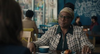 Movie still from “You Hurt My Feelings” (2023), directed by Nicole Holofcener – A woman sitting at a table with a cup of coffee; Medium shot, Over the shoulder angle