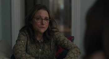 Movie still from “You Hurt My Feelings” (2023), directed by Nicole Holofcener – A woman sitting on top of a couch in a living room; Medium shot, Over the shoulder angle
