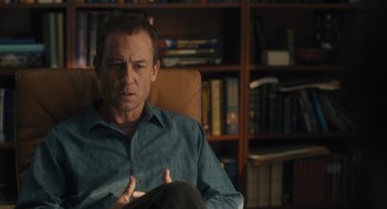 Movie still from “You Hurt My Feelings” (2023), directed by Nicole Holofcener – A man sitting in a chair in front of a book shelf; Medium shot, Over the shoulder angle