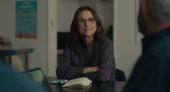 Movie still from “You Hurt My Feelings” (2023), directed by Nicole Holofcener – A woman sitting at a table in front of an open book; Medium shot, Over the shoulder angle