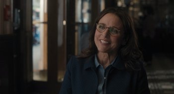 Movie still from “You Hurt My Feelings” (2023), directed by Nicole Holofcener – A woman in a blue jacket and glasses smiling; Close Up shot, Over the shoulder angle
