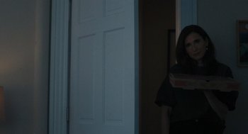 Movie still from “You Hurt My Feelings” (2023), directed by Nicole Holofcener – A woman standing in front of an open door holding a pizza box; Medium shot, Over the shoulder angle