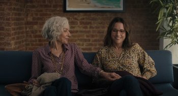 Movie still from “You Hurt My Feelings” (2023), directed by Nicole Holofcener – Two women sitting on a couch holding hands; Medium shot, Over the shoulder angle