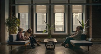 Movie still from “You Hurt My Feelings” (2023), directed by Nicole Holofcener – Three women sitting on a bench in front of a window; Wide shot, High angle