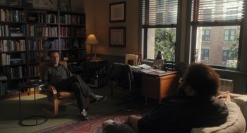 Movie still from “You Hurt My Feelings” (2023), directed by Nicole Holofcener – A man sitting on a chair in a living room next to a window; Wide shot, Over the shoulder angle