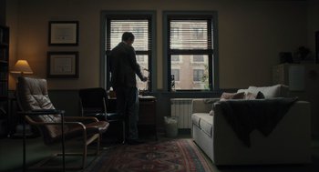 Movie still from “You Hurt My Feelings” (2023), directed by Nicole Holofcener – A man standing in front of a window in a room; Wide shot, High angle