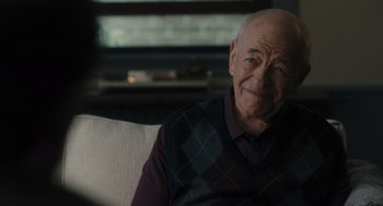 Movie still from “You Hurt My Feelings” (2023), directed by Nicole Holofcener – An older man sitting on a couch in a living room; Close Up shot, Over the shoulder angle