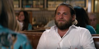 Movie still from “You People” (2023), directed by Kenya Barris – A man sitting at a table with a glass of water in front of him; Close Up shot, Over the shoulder angle